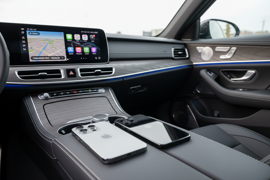 Two iPhones on car centre armrest with Apple CarPlay on touchscreen